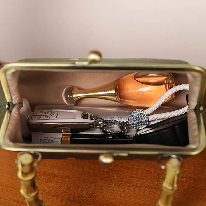 Bolso cruzado con asa de bambú y cadena de metal, piedras de Buda, plantas verdes, montañas