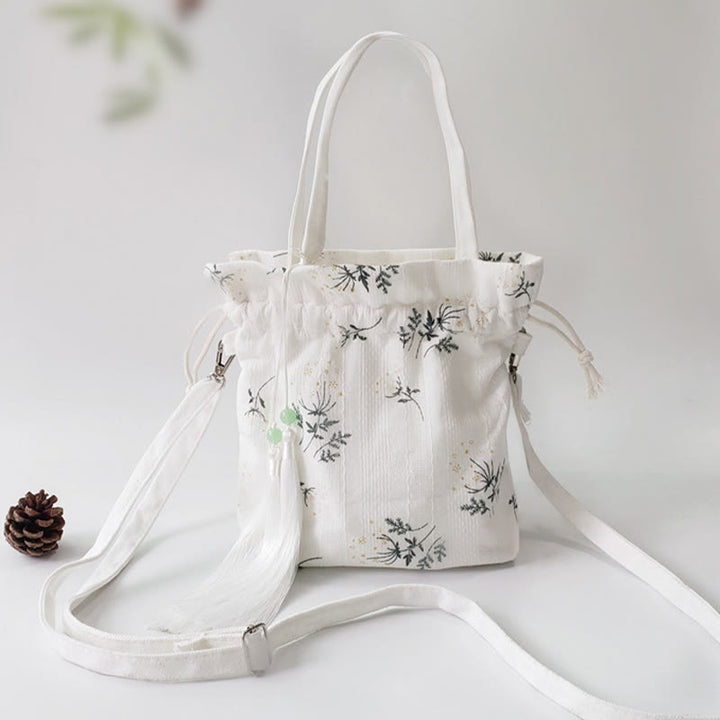 Bolso bandolera de lona con diseño de Buddha Stones, flores blancas y hojas verdes.