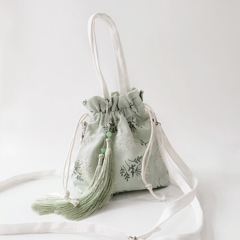 Bolso bandolera de lona con diseño de Buddha Stones, flores blancas y hojas verdes.