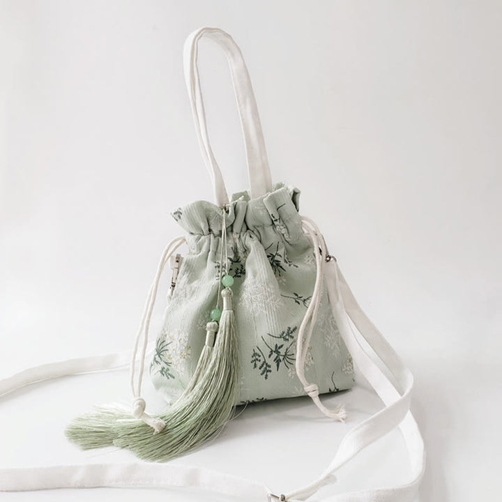 Bolso bandolera de lona con diseño de Buddha Stones, flores blancas y hojas verdes.