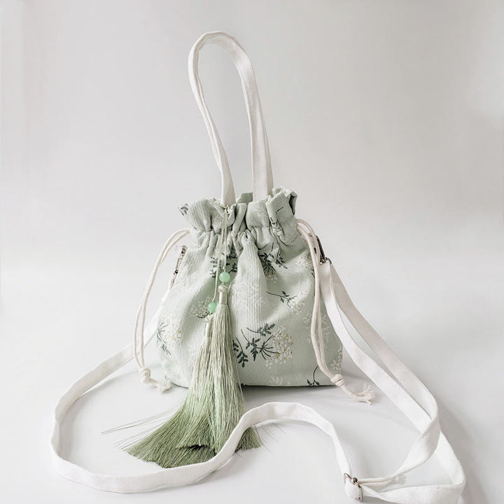 Bolso bandolera de lona con diseño de Buddha Stones, flores blancas y hojas verdes.
