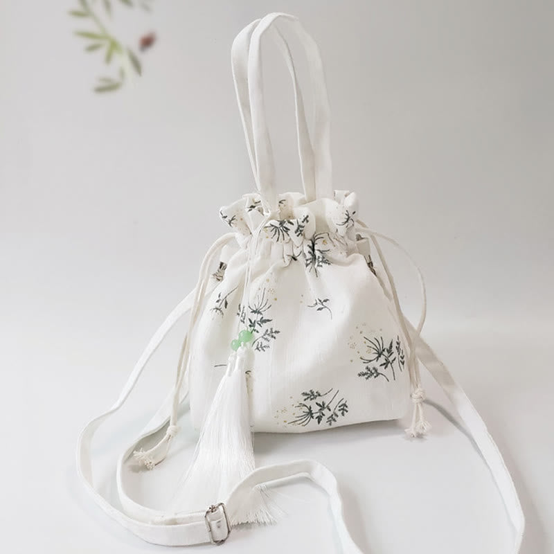Bolso bandolera de lona con diseño de Buddha Stones, flores blancas y hojas verdes.