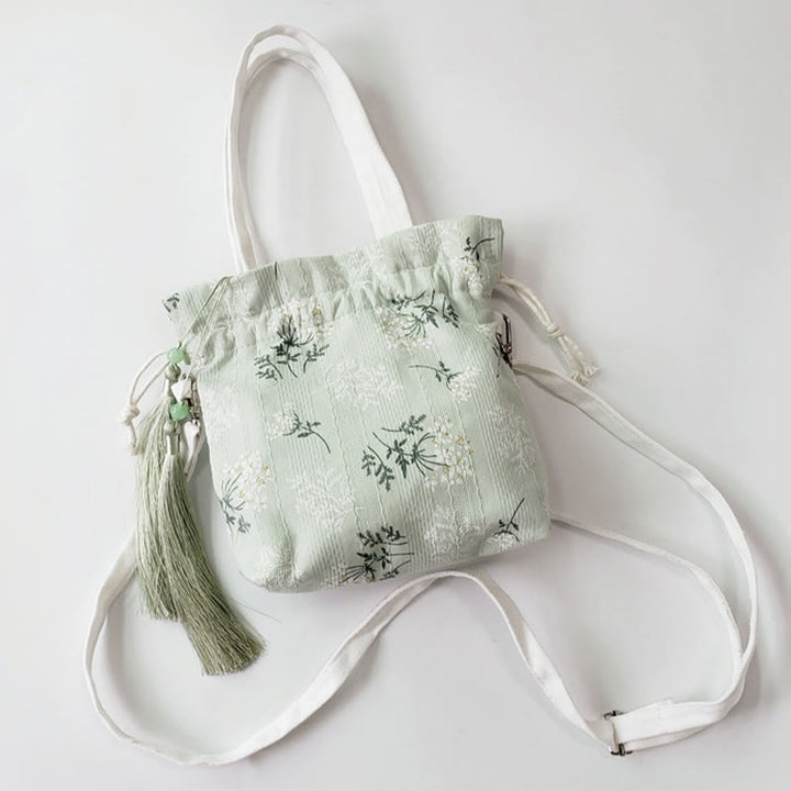 Bolso bandolera de lona con diseño de Buddha Stones, flores blancas y hojas verdes.