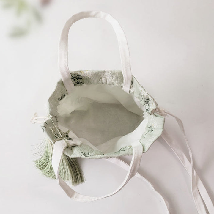 Bolso bandolera de lona con diseño de Buddha Stones, flores blancas y hojas verdes.