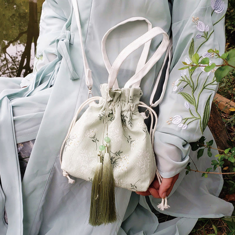 Bolso bandolera de lona con diseño de Buddha Stones, flores blancas y hojas verdes.