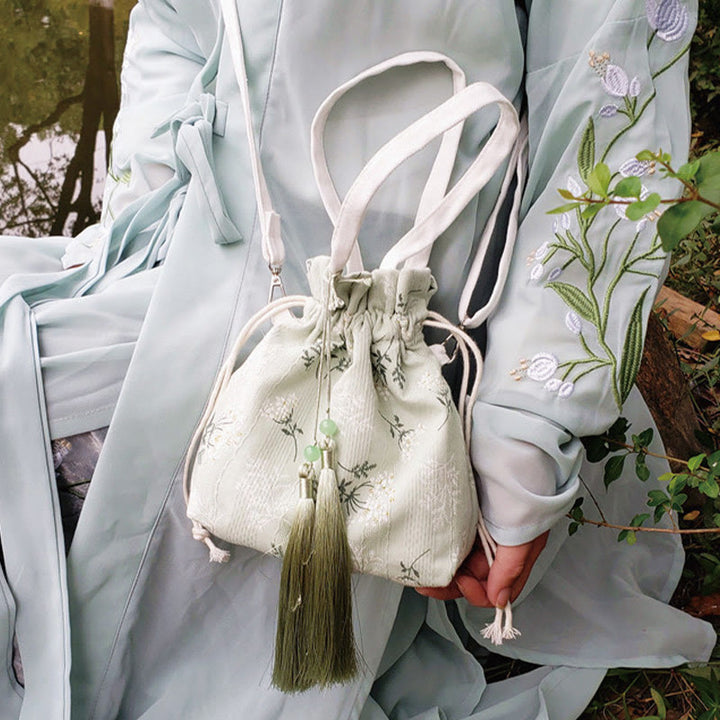 Bolso bandolera de lona con diseño de Buddha Stones, flores blancas y hojas verdes.