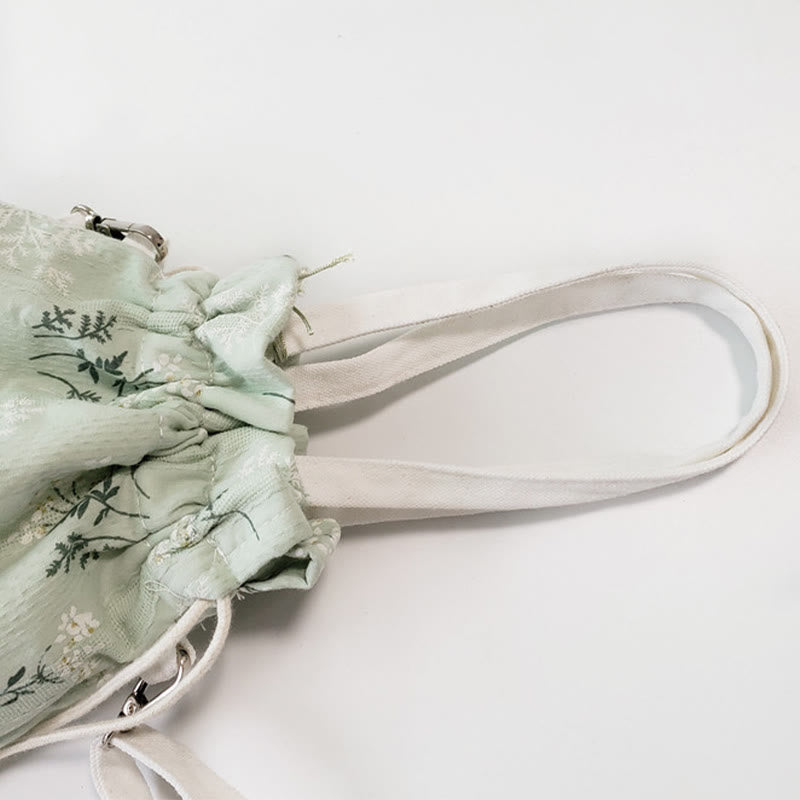 Bolso bandolera de lona con diseño de Buddha Stones, flores blancas y hojas verdes.