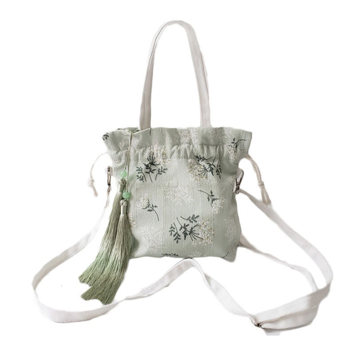 Bolso bandolera de lona con diseño de Buddha Stones, flores blancas y hojas verdes.