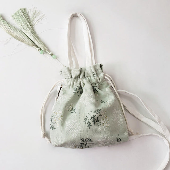 Bolso bandolera de lona con diseño de Buddha Stones, flores blancas y hojas verdes.