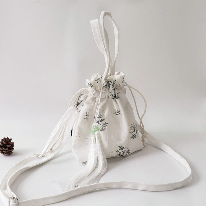 Bolso bandolera de lona con diseño de Buddha Stones, flores blancas y hojas verdes.