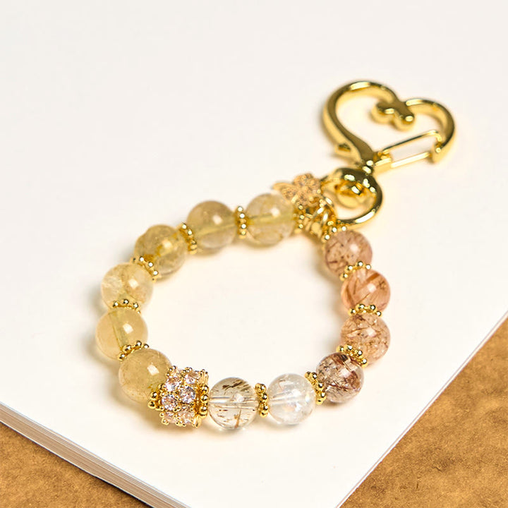 Llavero colgante de cuarzo rutilado dorado con Buddha Stones que simboliza la buena fortuna.