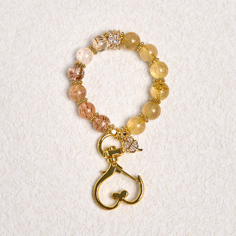 Llavero colgante de cuarzo rutilado dorado con Buddha Stones que simboliza la buena fortuna.