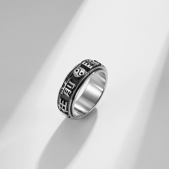 Anillo giratorio de acero titanio con letras en equilibrio y calma