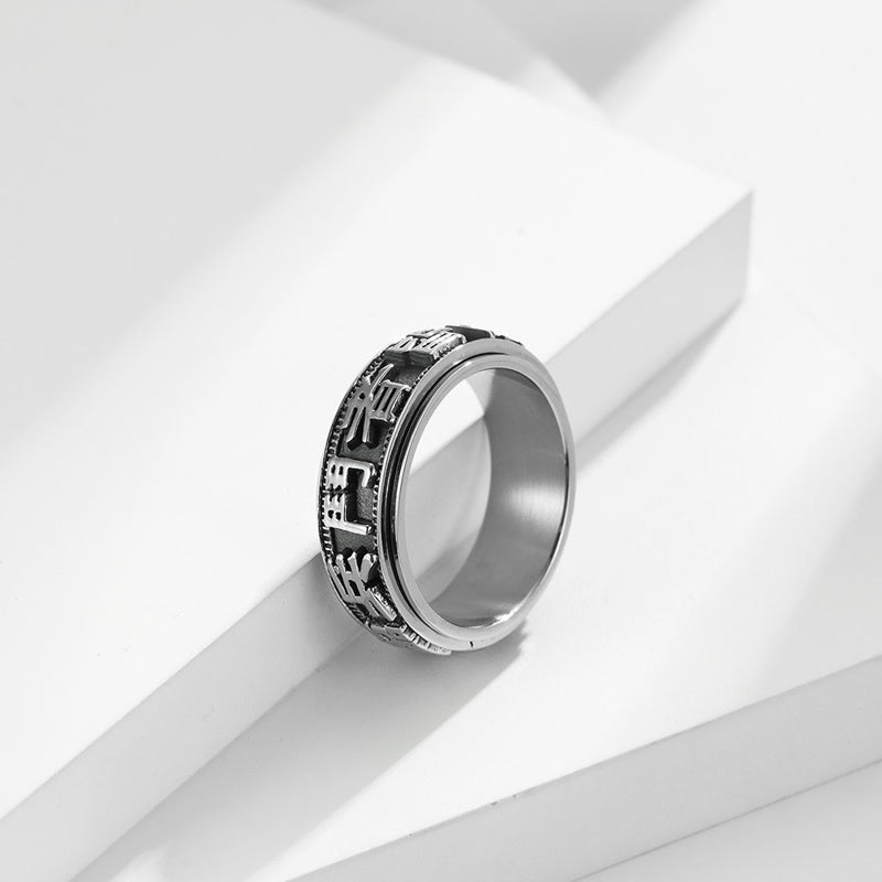 Anillo giratorio de acero titanio con letras en equilibrio y calma