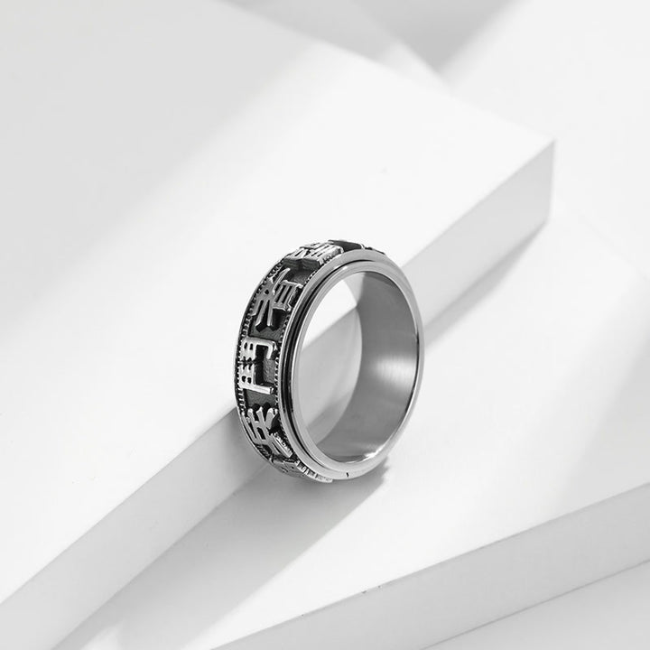Anillo giratorio de acero titanio con letras en equilibrio y calma